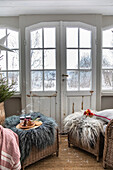 Winter garden with two woven armchairs and fur throws