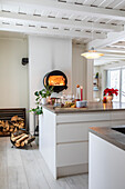 Modern kitchen with kitchen island and round wall-mounted fireplace in black metal