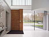 Holztür und Ganzglasfassade in großzügigem Eingangsbereich