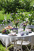 Laid garden table with lavender bouquets and porcelain crockery in the summer garden