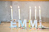 Candle holder in letter form "EMMI" with colourful confetti on the table