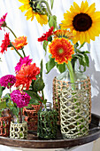 Colourful summer flowers in woven vases on a wooden table