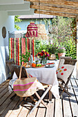 Set wooden table on a covered terrace with colourful summer decorations