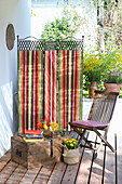 Striped screen on wooden terrace next to wooden chair and chest