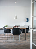 Dining room with black leather chairs and white hanging lamp