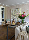 Living room with bouquet of flowers on modern side table and large painting on the wall