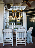 Woven rattan furniture and hanging lamps on a covered veranda