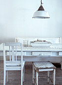 Vintage-style dining area with white wooden furniture and metal lamp