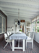 Covered veranda with white dining table and white seating