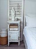 Shabby chic bedside table with Madonna statue and storage boxes in the bedroom