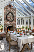 Set dining table in conservatory with fireplace and brick wall