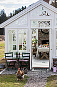 White greenhouse with set table and chicken in front of entrance door