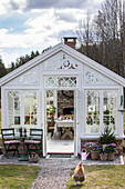 White greenhouse with group of tables, plants and decorative elements in the garden