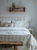 Bedroom with white crocheted bedspread and wooden shelf