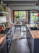 Narrow kitchen with wooden counters, black cupboards and a view of the dining area