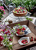 Sommertorte mit frischen Beeren und Kiwi auf einer Gartenterrasse