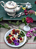 Tea cakes decorated with berries and flowers on a rustic wooden table