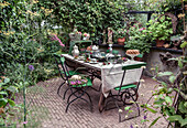 Laid table in the garden surrounded by lush greenery and plants