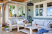 Upholstered wooden sofa corner with plants and lantern on the veranda