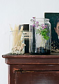 Glass jar with flowering herb on antique chest of drawers