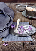 Vintage zinc plate with candied purple lilacs on a rustic wooden table