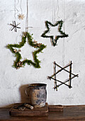 Natural Christmas decoration with stars made of moss and twigs on a white wall