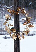 Golden wreath of leaves on wooden posts against a wintry backdrop