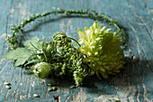 Grüner Blumenkranz mit Chrysantheme und Knospen auf verwittertem Holztisch