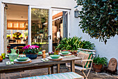 Laid patio table with plants and view into the dining room