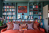 Living room with built-in bookshelf wall, red sofa and patterned cushions