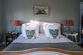 Bedroom with patterned wallpaper, double bed and decorative pillows