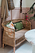 Rattan bench with patterned cushions and pink wall panelling