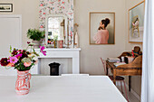 Dining room with floral pattern wallpaper and bouquet of flowers on wooden table