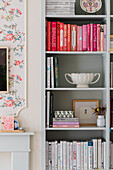 Pastel-coloured bookshelf with books sorted by colour