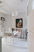 Dining room with white wooden table, metal wicker chairs and picture shelf