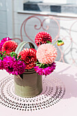 Colourful dahlias (Dahlia) in a green watering can on a stamped metal table