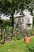 White garden shed and wooden picket fence in the summer garden