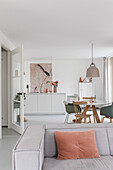 Open-plan living and dining area with white furnishings and pastel-coloured accents