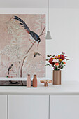 Minimalist kitchen with pink wall art and flower vase on white worktop