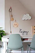 Modern desk with sage green chairs and playful wall decoration