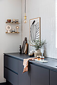 Modern kitchen with black units, ceramic crockery and minimalist wall mural