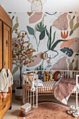 Baby room with wooden cot, wallpaper with botanical pattern and plush toys