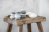 Stacked, painted pebbles and tea lights on a rustic wooden stool