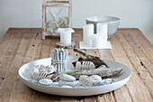 Decorative tray with driftwood, painted stones and cardboard fish on a wooden table