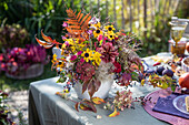 Autumnal bouquet of sunflower (helenium) and fern on a laid garden table