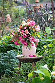 Colourful bouquet of roses (pink) on antique stool in summer garden