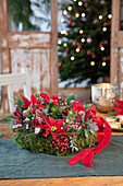 Christmas wreath with holly, berries and ribbon on wooden table