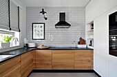 Modern kitchen with wooden elements and white tiled wall in Stegny, Warsaw