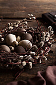 Osternest aus Weidenkätzchen mit Eiern auf Holztisch