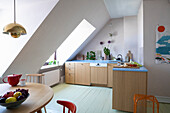 Bright kitchen in pastel colours with sloping roof and wooden furniture